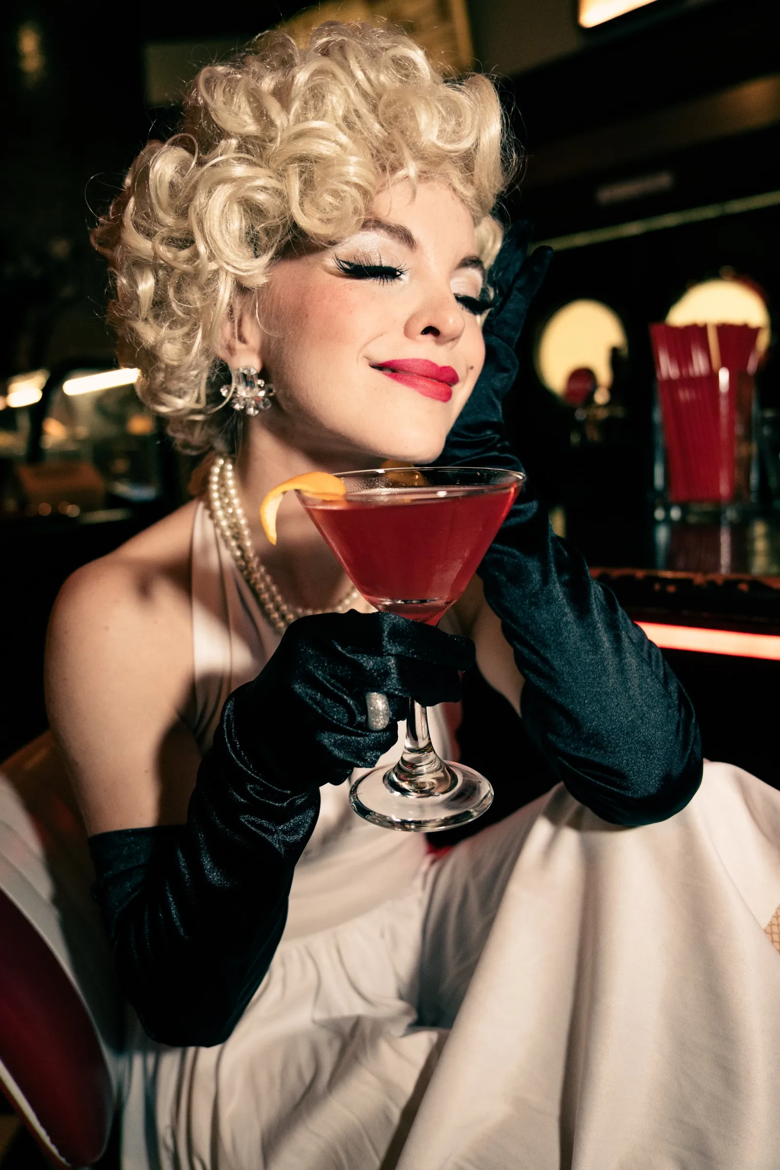 Modelka ve stylu Marilyn Monroe upíjí rudý koktejl