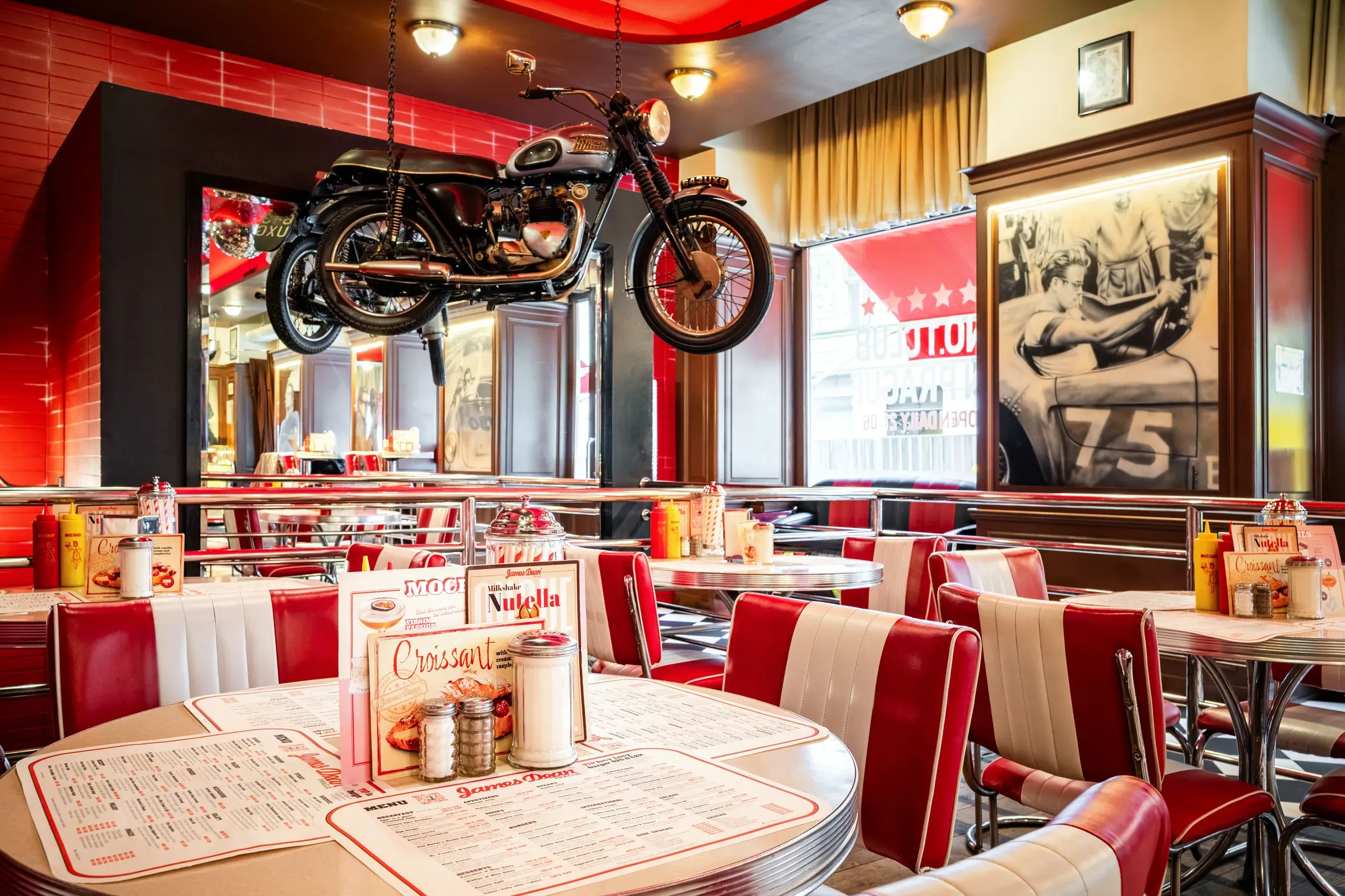 Rote Sitznischen im Diner, ein Motorrad an der Wand und ein Airbrush-Gemälde